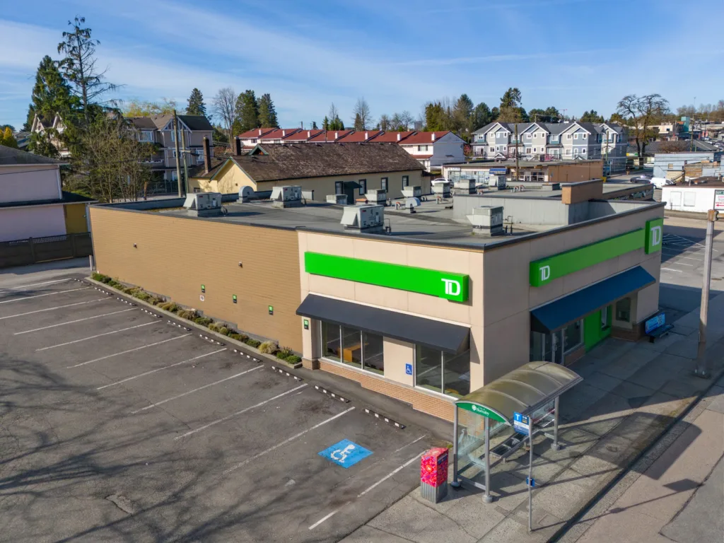Hastings & Sperling corner exterior with surface parking and bus stop on Hastings Street, Burnaby