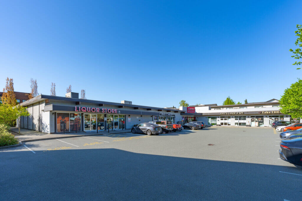 Queens Plaza street-level view of retail storefronts and parking lot