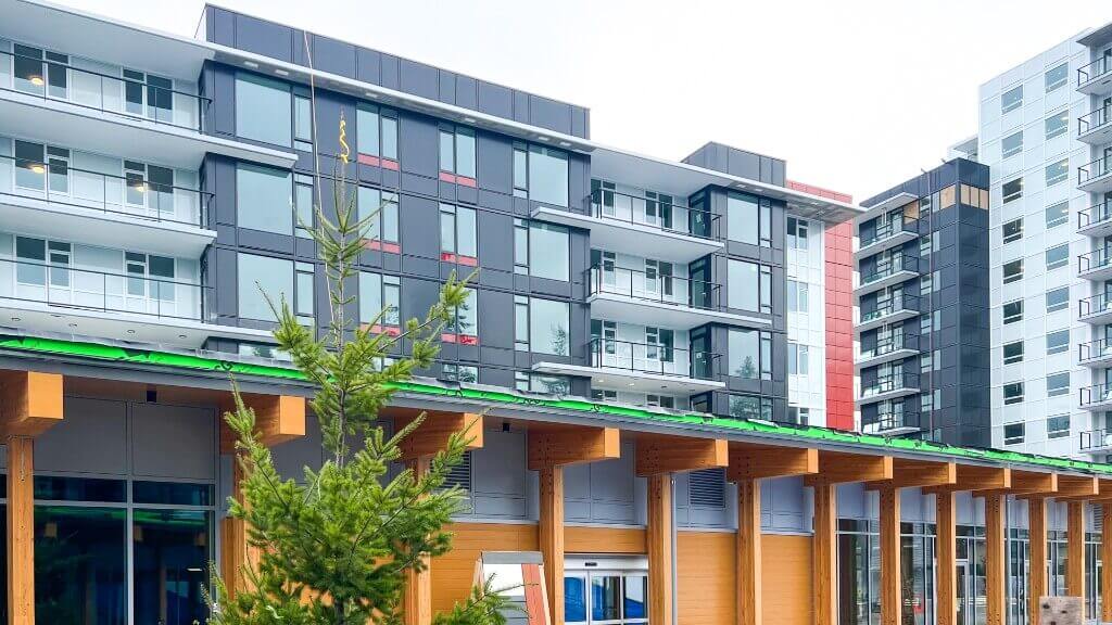 Lelem Village University Blvd Building exterior showing wood-beam canopy entrance and adjacent buildings