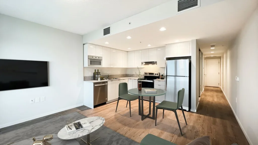 Lelem Village University Blvd Building staged dining area and kitchen with stone countertops and modern cabinetry