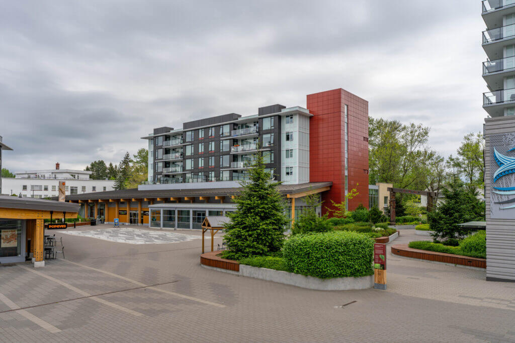 Lelem Village University Blvd Building and landscaped courtyard with evergreen trees