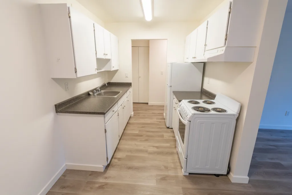 Galley kitchen with white cabinets and appliances at Charles Manor Charles St Unit 201