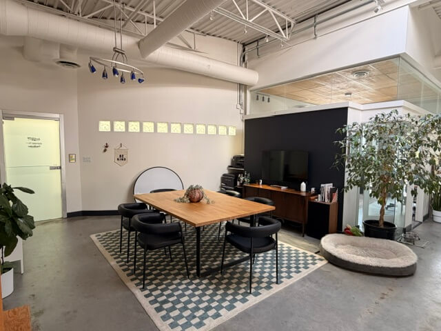 Open-plan office with meeting table and exposed ductwork in Unit 212 at 1737 West 3rd Avenue