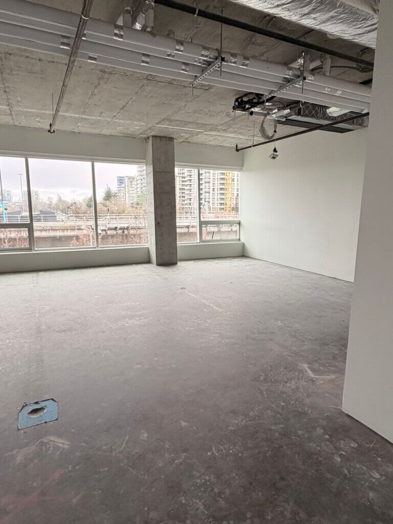Open-plan office shell with exposed concrete and east-facing windows at 5599 No. 3 Road Unit 430